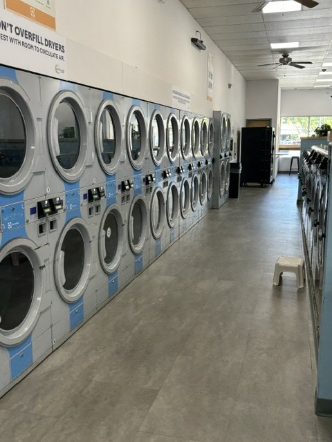Inside the Scrubs Laundry self-service laundromat in Chelsea — a long row of clean, high-capacity stacked machines